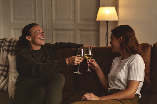 To kvinner skåler med hvitvin i en sofa